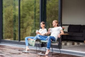 Ein Paar sitzt auf eine Holzterasse und genießt eine Tasse Kaffee