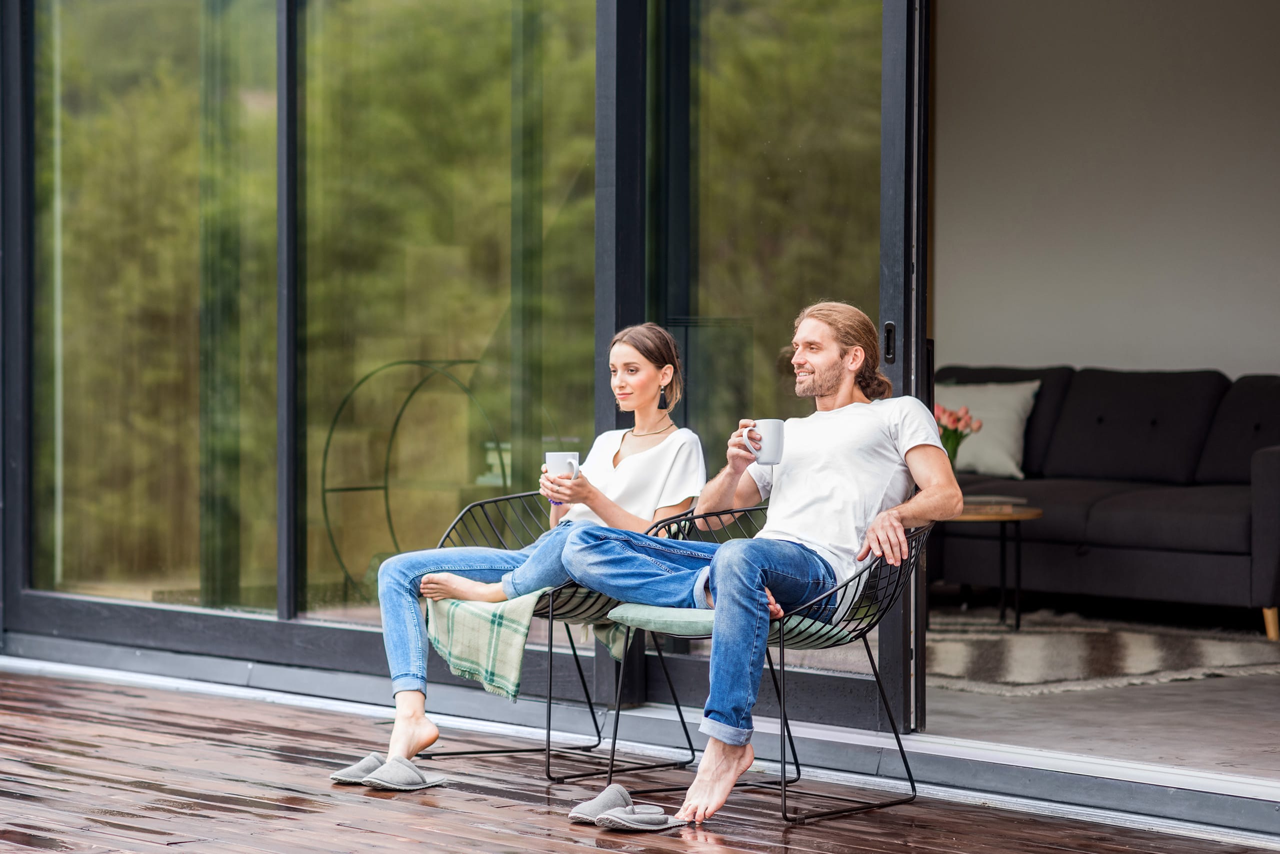 Ein Paar sitzt auf eine Holzterasse und genießt eine Tasse Kaffee